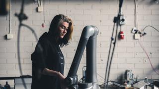 Kuvassa nuori henkilö tutkii robotiikkalaitetta