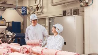 Fazer employees smiling in a factory setting.